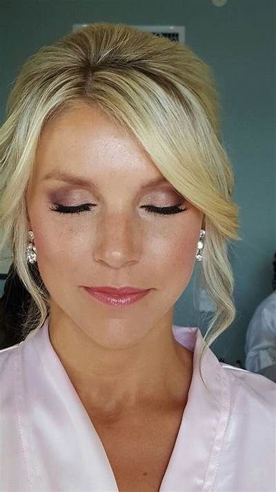 a woman with blonde hair wearing earrings and a white shirt