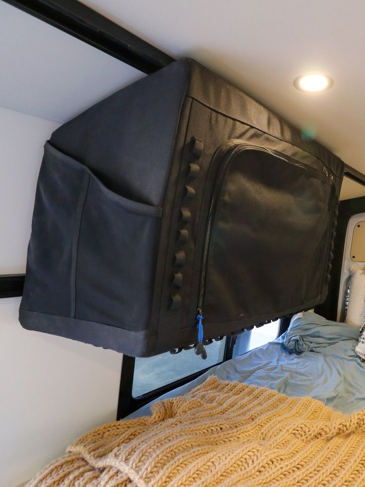 the back end of a bed with a black bag on it's headboard