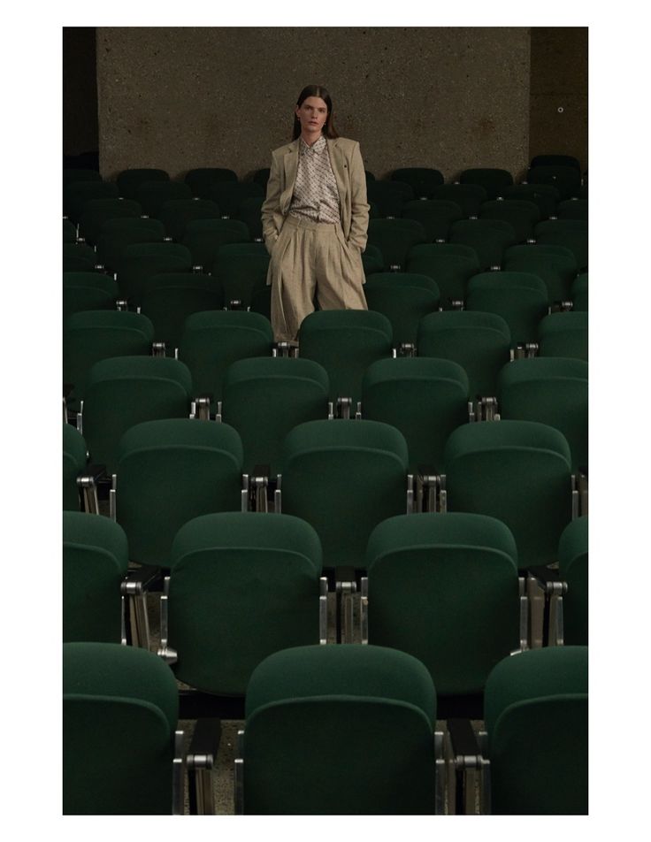 a woman standing in the middle of rows of green chairs