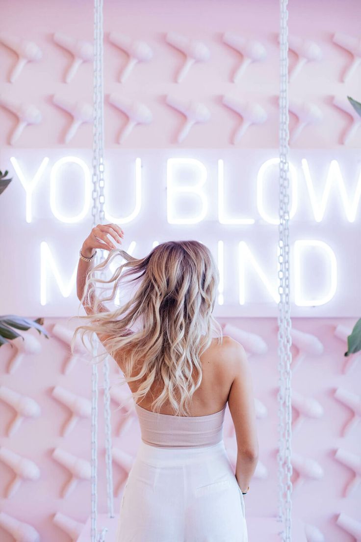 a woman standing in front of a neon sign that says you blow mind