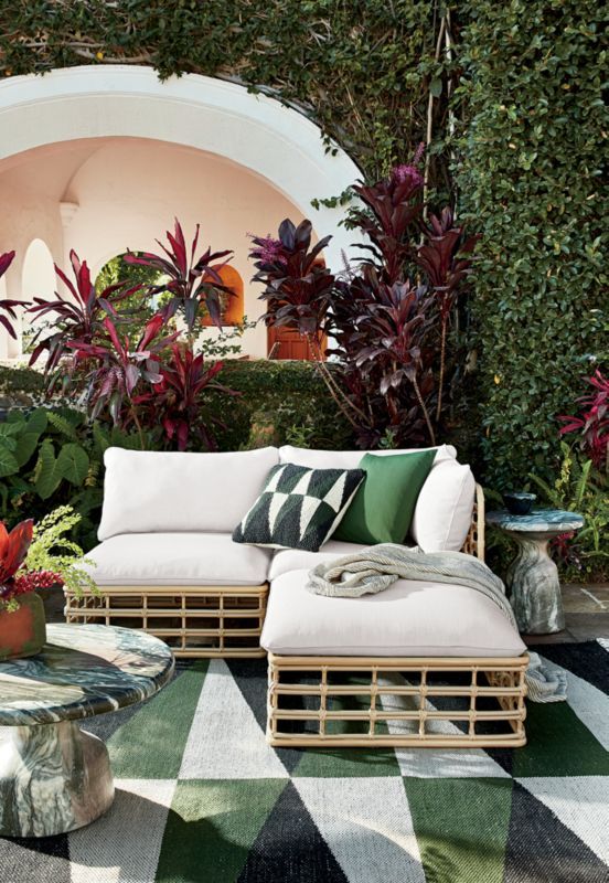 an outdoor living area with couches, tables and potted plants in the background