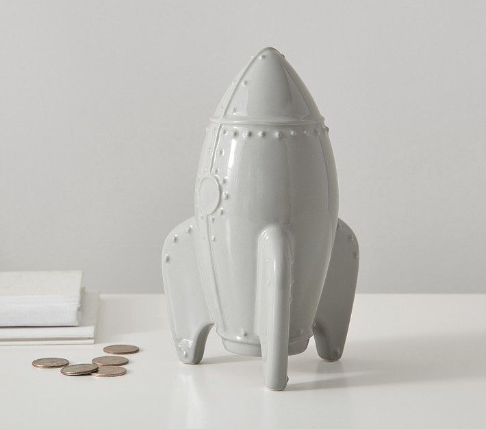 a white toy rocket ship next to some coins