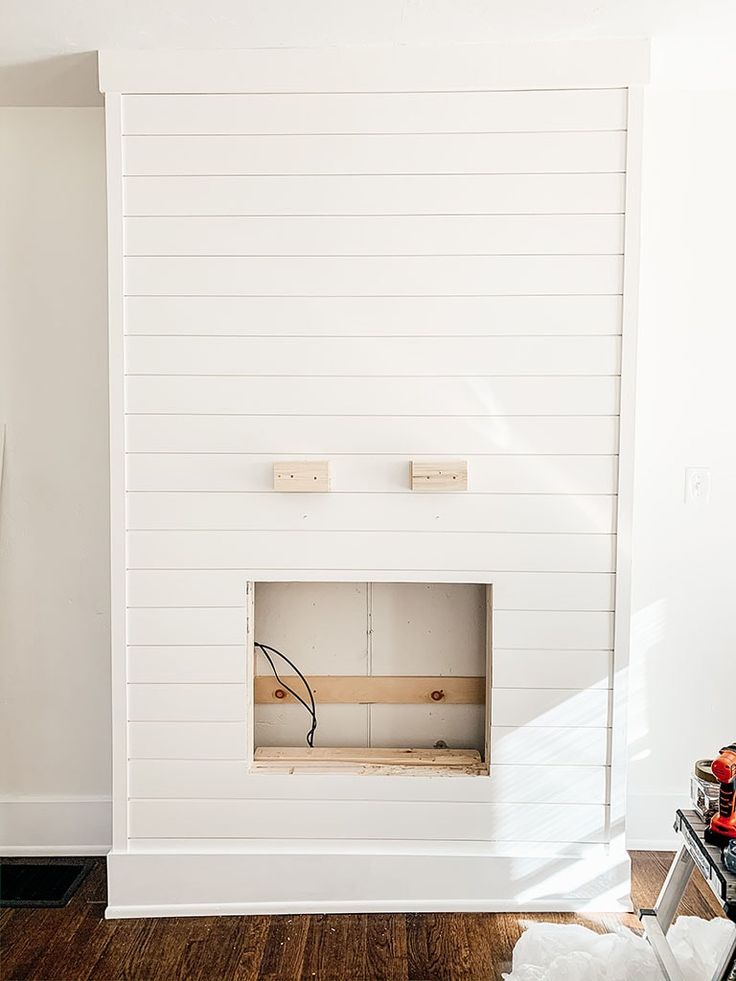 a white fireplace in a living room with wood flooring