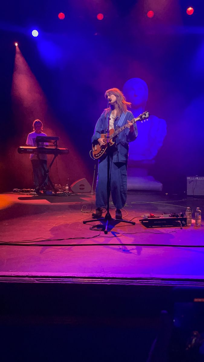 a man standing on top of a stage holding a guitar