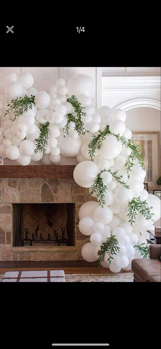 a fireplace with balloons and greenery on it