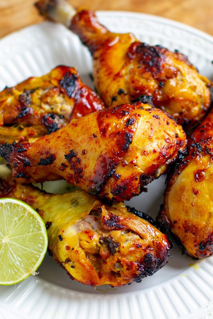 grilled chicken wings with lime wedges on a white plate, ready to be eaten