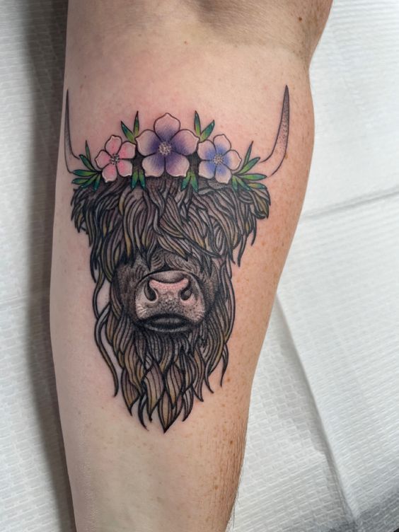 a tattoo on the leg of a man with flowers in his hair and a bull's head