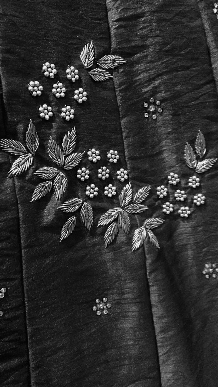 black and white photograph of embroidered fabric with flowers on it's side, closeup