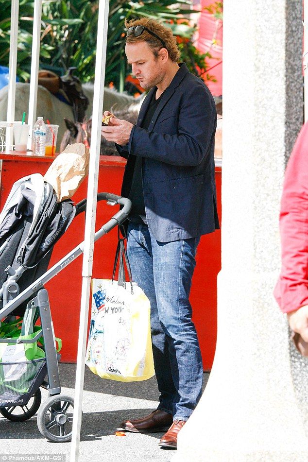 a man standing next to a stroller and holding a baby in it's hand