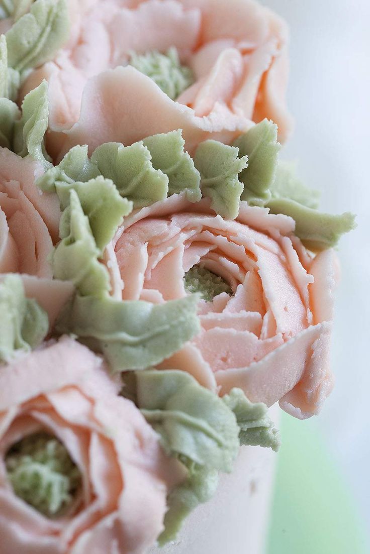 a bouquet of pink and green flowers sitting on top of a white tablecloth covered cake