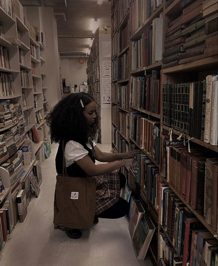 a woman sitting on the floor in front of a book shelf filled with books and holding onto a brown bag