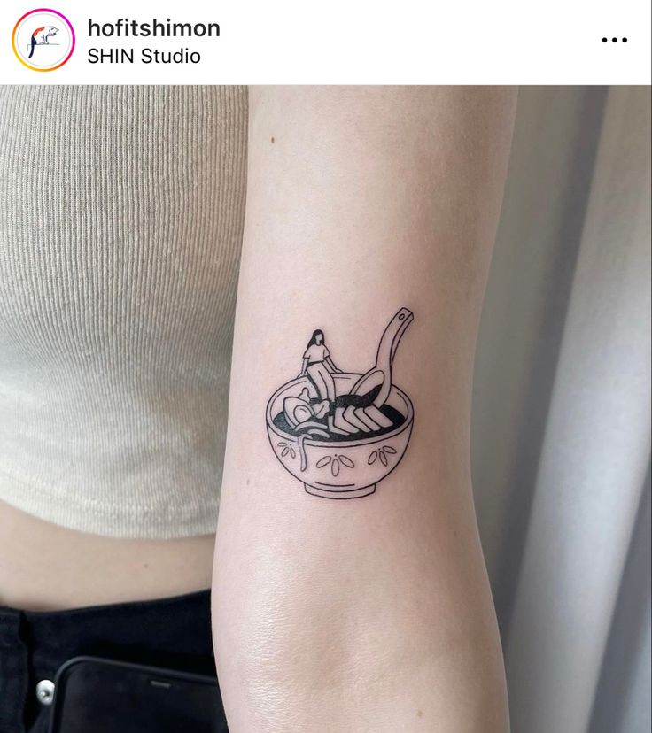 a woman's arm with a small tattoo of a bowl of soup on it