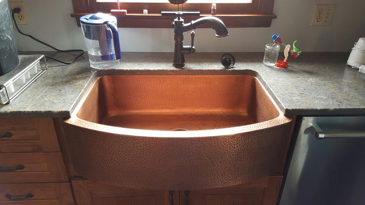 a copper sink in a kitchen under a window