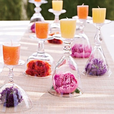 a table topped with wine glasses filled with different types of candles and flowers on top of it