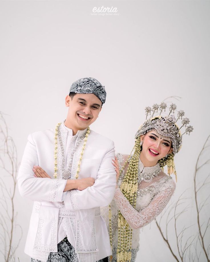 a man and woman dressed in traditional thai garb standing next to each other with their arms crossed