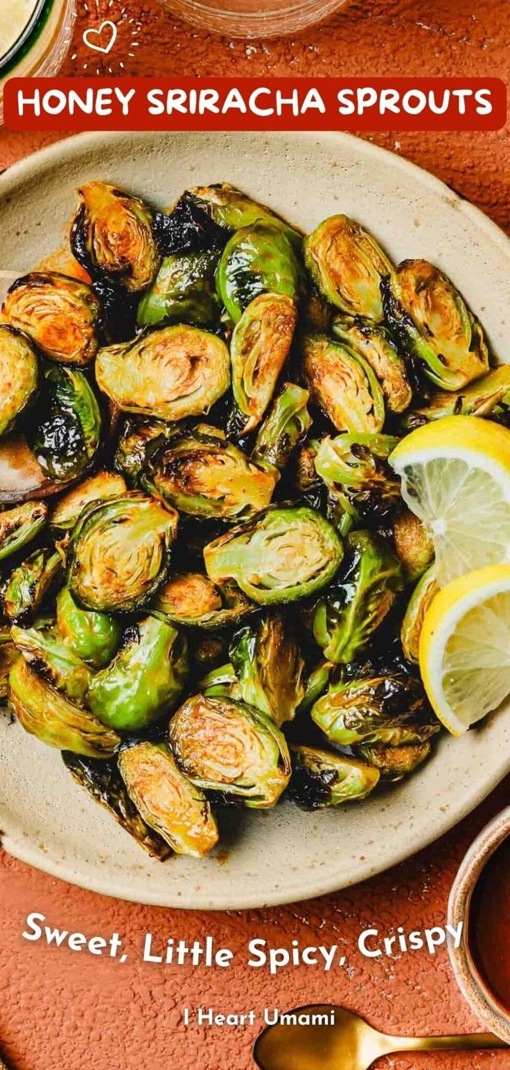 a white plate topped with brussel sprouts and lemon wedges