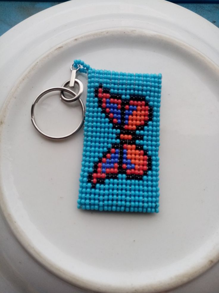 a cross stitch keychain is sitting on a plate