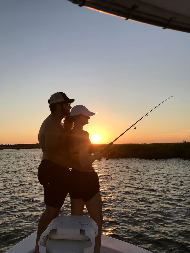 two people on a boat fishing at sunset