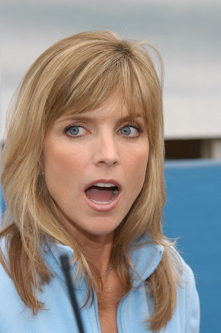 a woman with blonde hair and blue eyes is making a surprised face as she stands in front of a microphone