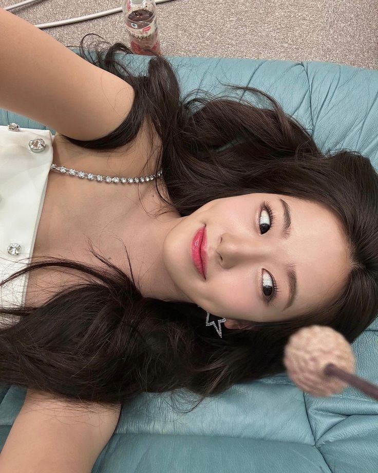 a woman laying on top of a blue couch holding a hair dryer in her hand