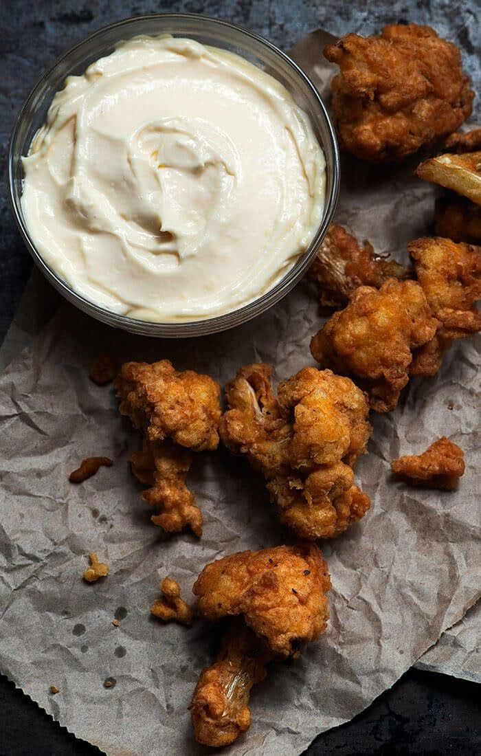 some fried food is on a piece of wax paper next to a bowl of dip