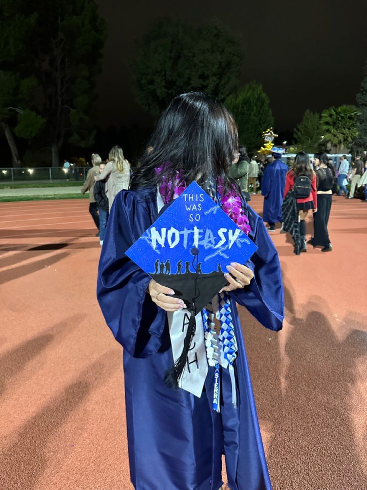 a woman wearing a graduation gown and holding a blue sign that says not to task