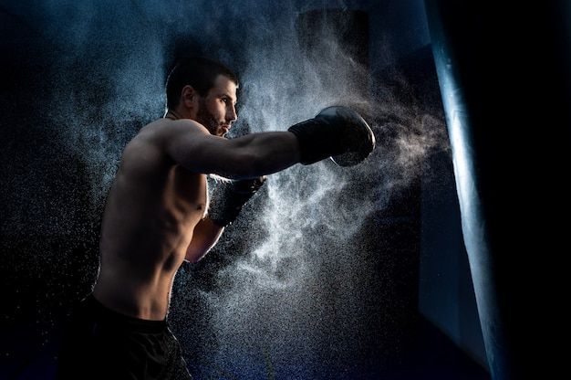 a shirtless man is boxing in the dark