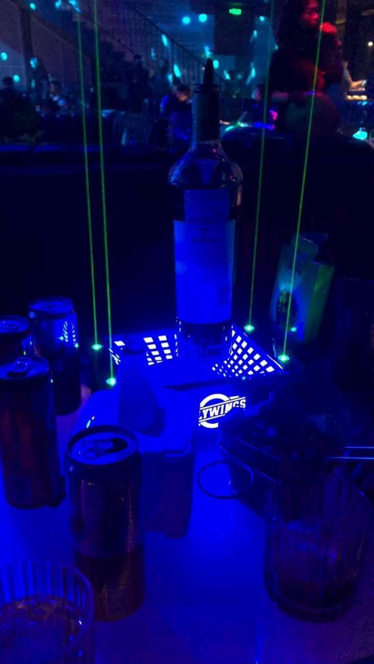 there is a table that has some drinks on it with lights around the table and bottles