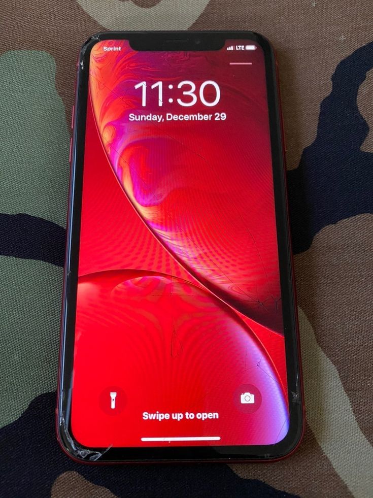 an iphone xr sitting on top of a camouflage print surface with the screen open