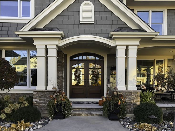 the front entrance to a house with two large windows