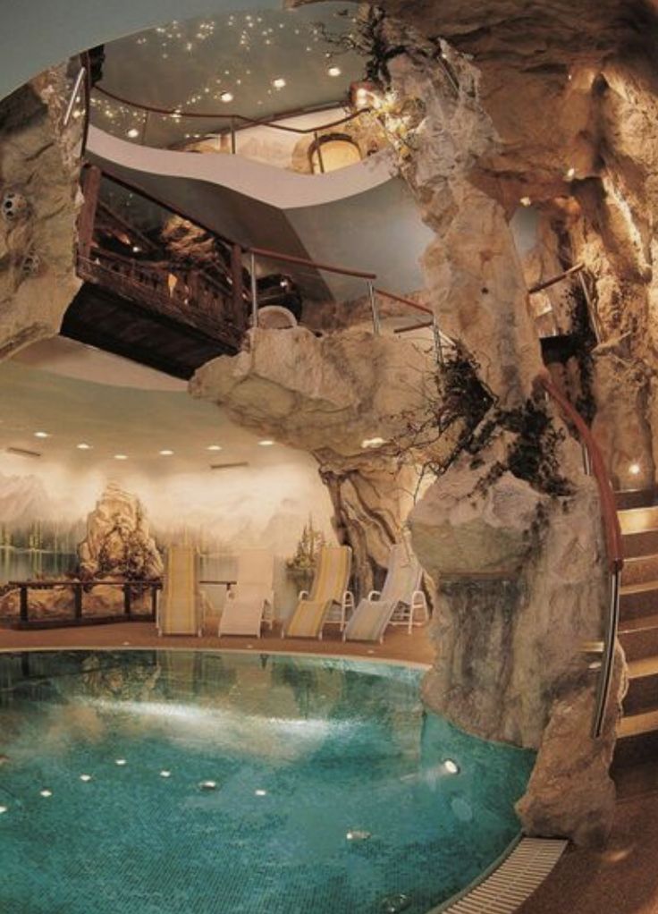 a large indoor swimming pool with waterfall and steps leading up to the upper floor area