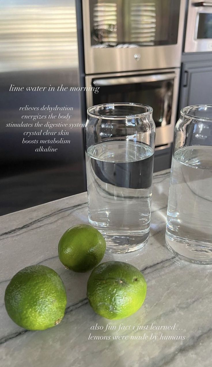 three limes are sitting on the counter next to two glasses with water in them