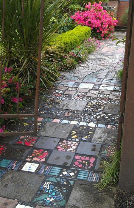 an open gate leading into a garden with flowers and plants in the background, on a cobblestone path