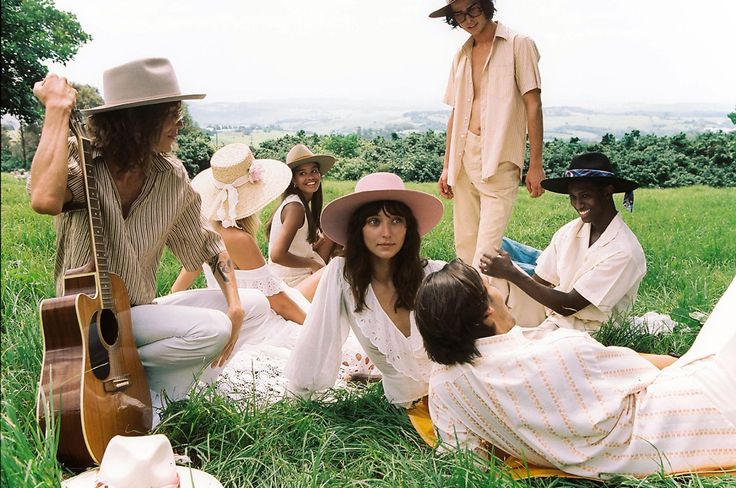 a group of people sitting on top of a lush green field next to each other