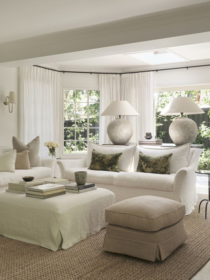 a living room filled with white furniture and lots of pillows on top of the couches