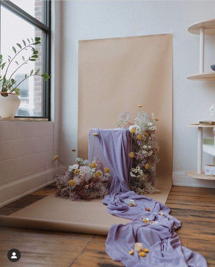 a room with flowers on the floor next to a large piece of paper that has been rolled down