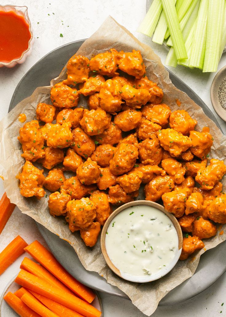 chicken wings with ranch dressing and carrots on a plate next to celery sticks