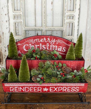 a red wagon filled with christmas trees and pine cones sitting on top of a wooden table