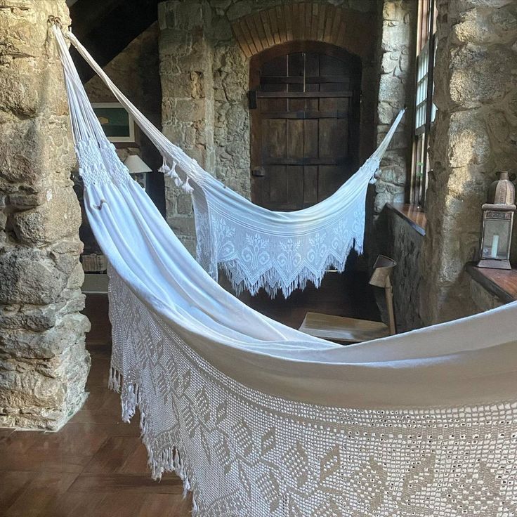 a white hammock hanging from a stone wall