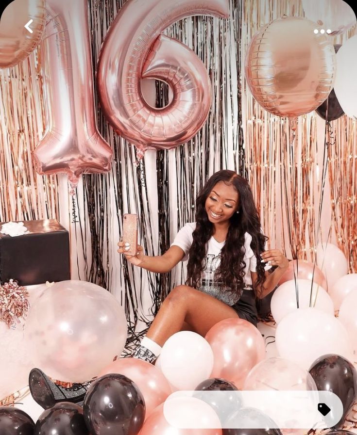 a woman sitting in front of balloons and streamers with the number 16 on it