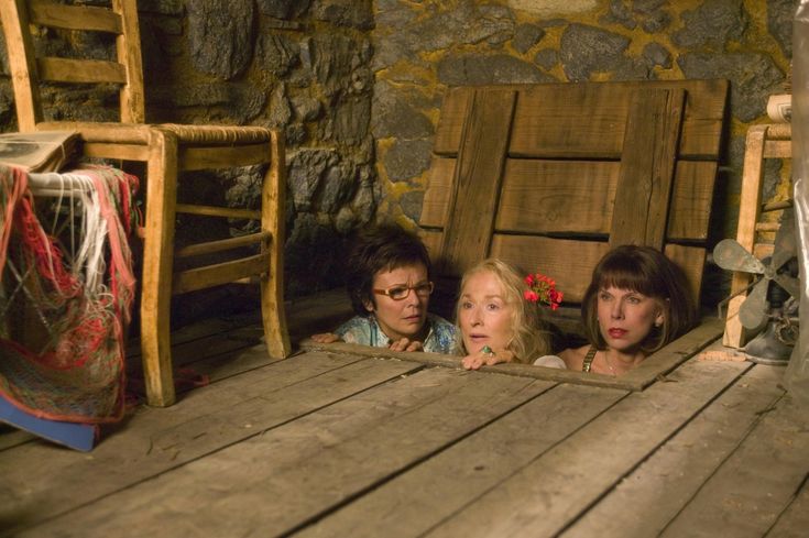 three people are sitting on a wooden porch