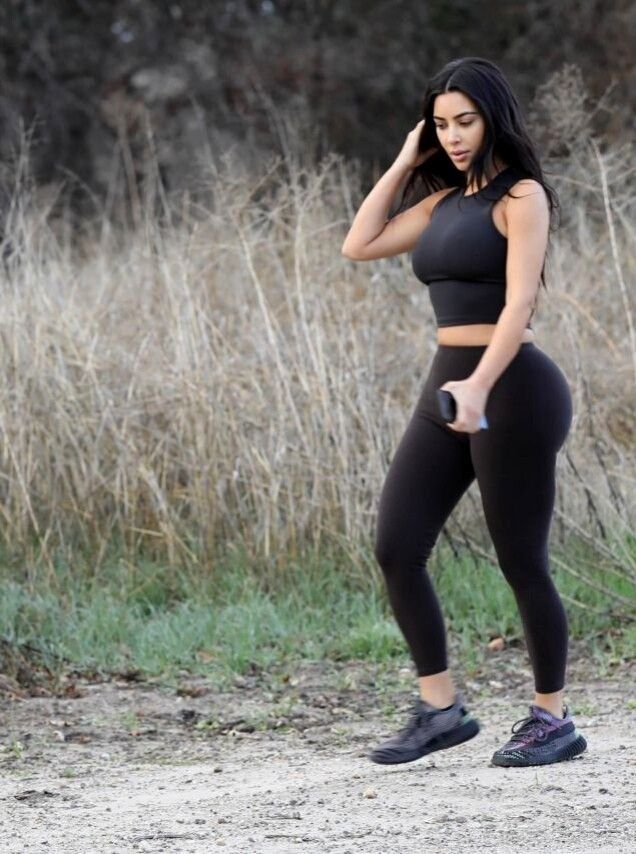 a woman in black sports bra top and leggings holding a cell phone to her ear