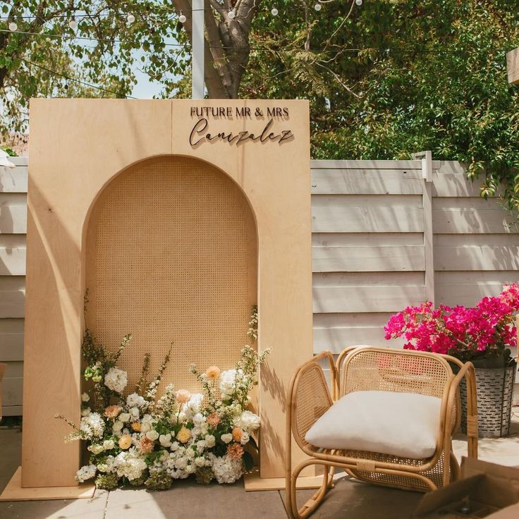 a chair sitting in front of a fake arch with flowers on it and a sign that says put me here & always complete