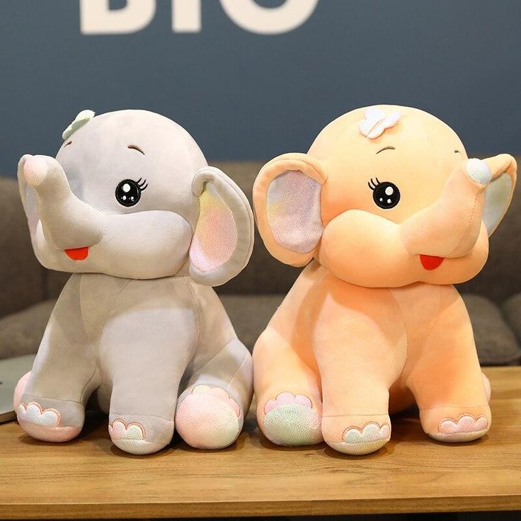 two stuffed elephants sitting next to each other on a table