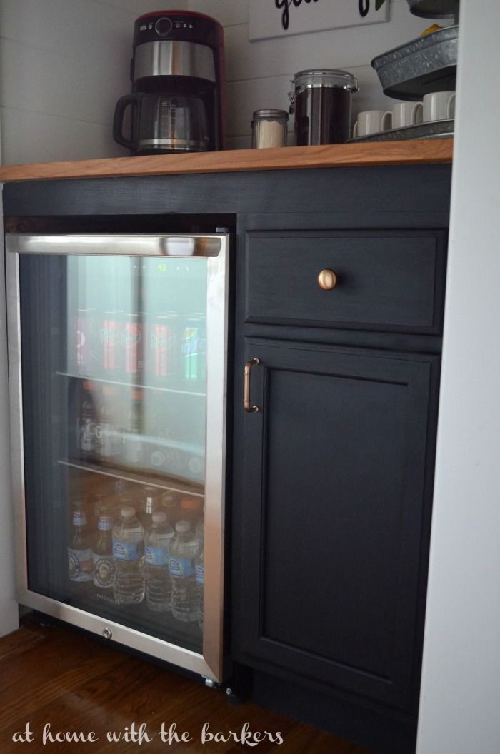 an open refrigerator door in a kitchen next to a counter with jars and cups on it