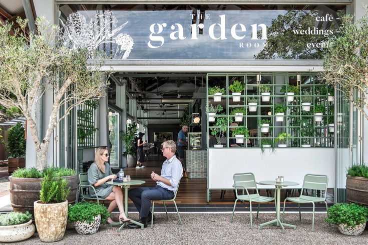 two people sitting at tables in front of a garden shop