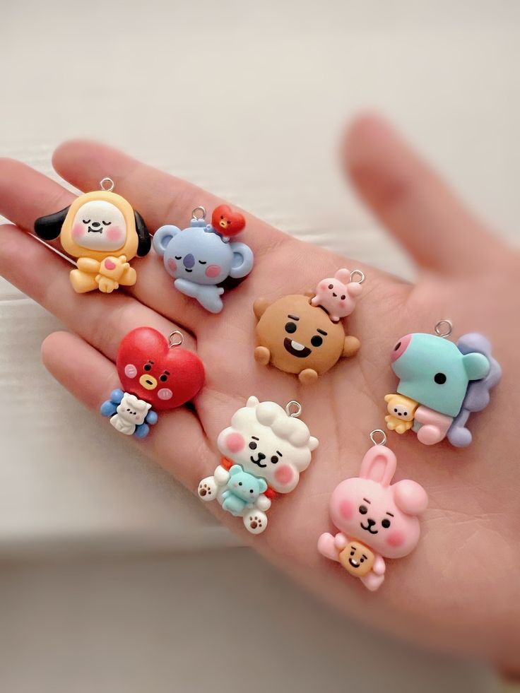 a person's hand holding several small animal charms on it, all in different colors