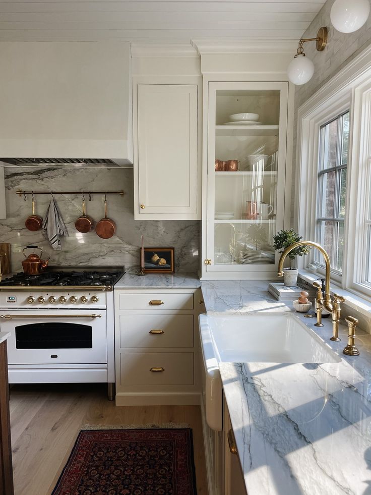 a kitchen with marble counter tops and white cabinets, along with an area rug on the floor