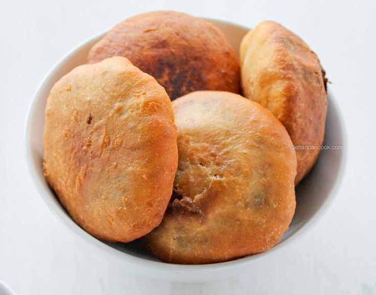 four rolls in a white bowl on a table