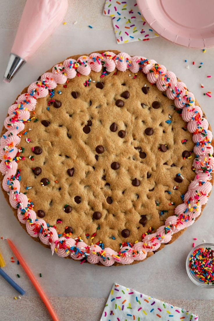 a large cookie cake with pink frosting and sprinkles on the top